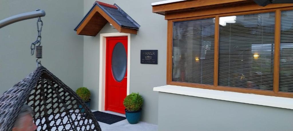 uma rede em frente a um edifício com uma porta vermelha em Harbour View Bed & Breakfast em Castletownbere