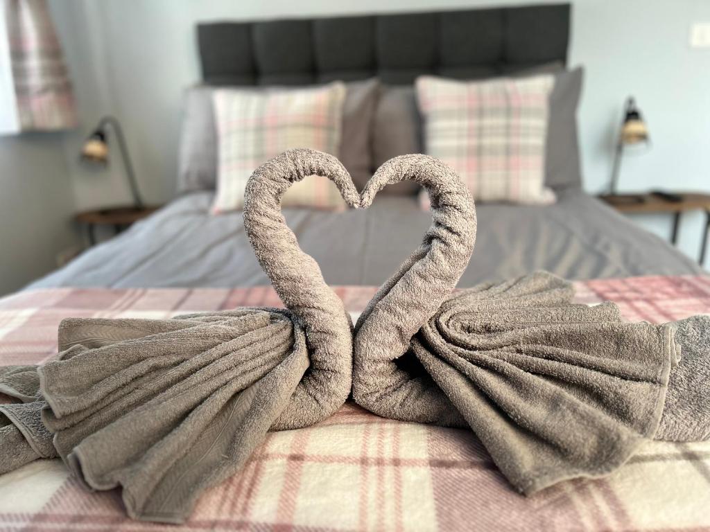 two towels in the shape of a heart on a bed at Dana’s bungalow in Horley