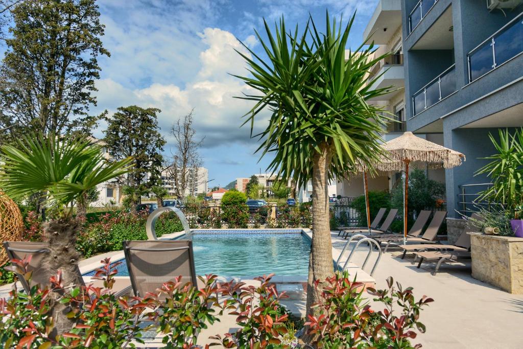 a swimming pool with a palm tree next to a building at Miami apartments in Ulcinj