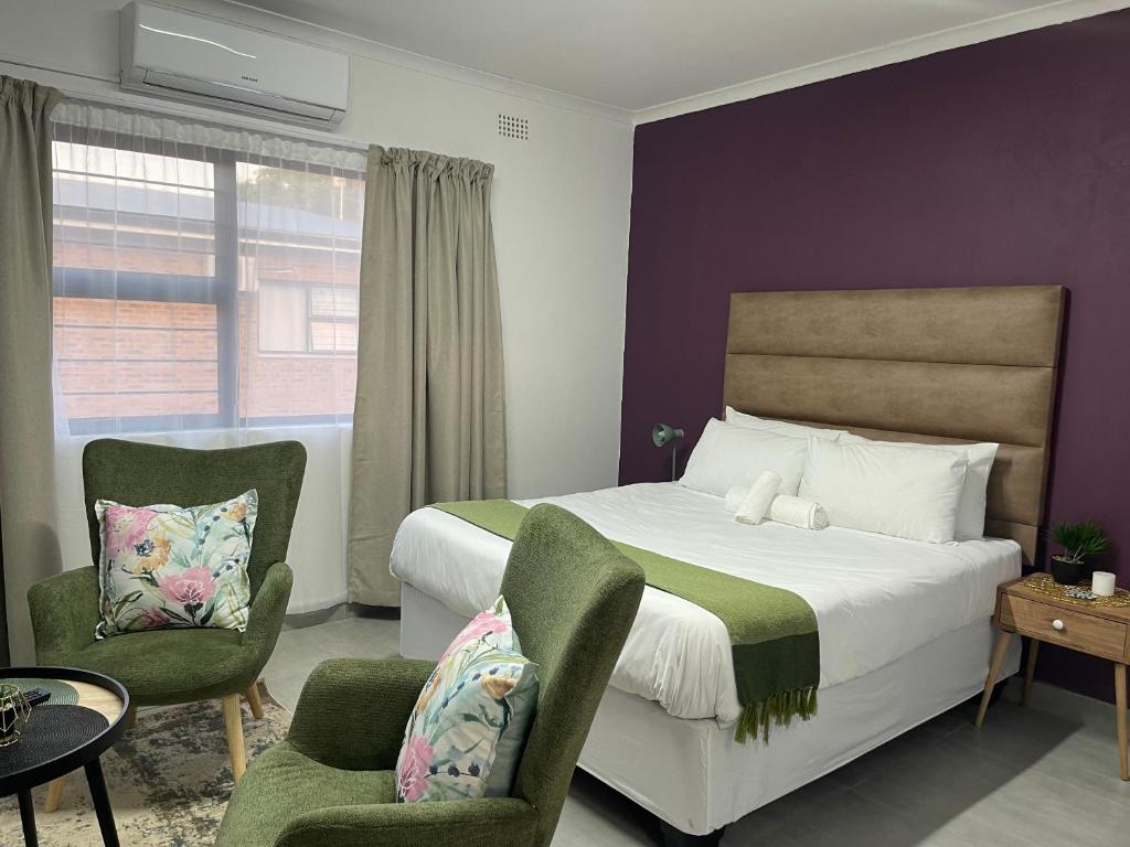 a bedroom with a bed and two chairs at Pristine Guest Apartments in Mthatha