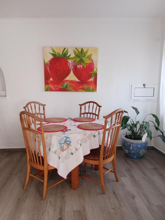 a table with four chairs and a painting of strawberries at Saint Peter´s House in Angra do Heroísmo