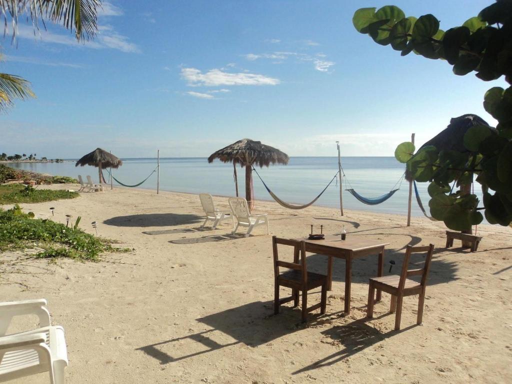 una playa con sillas, mesa y sombrillas en Hotel Maya Luna Adults Only, en Mahahual