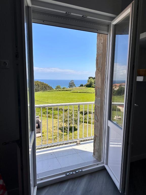 a door to a balcony with a view of the ocean at Miguelón in Bañugues