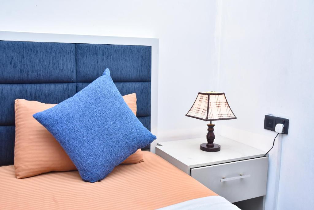 a bed with a blue pillow and a lamp on a night stand at Victoria Hideout in Digana
