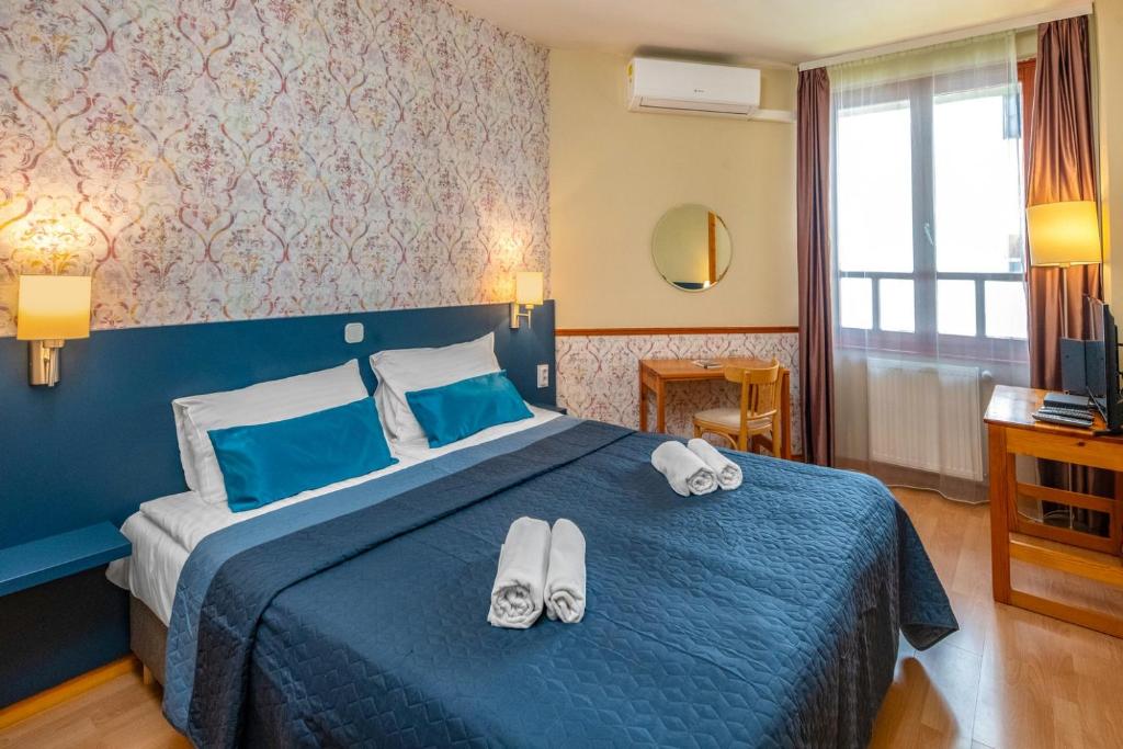 a bedroom with a blue bed with towels on it at Corvin Hotel Budapest Residence in Budapest