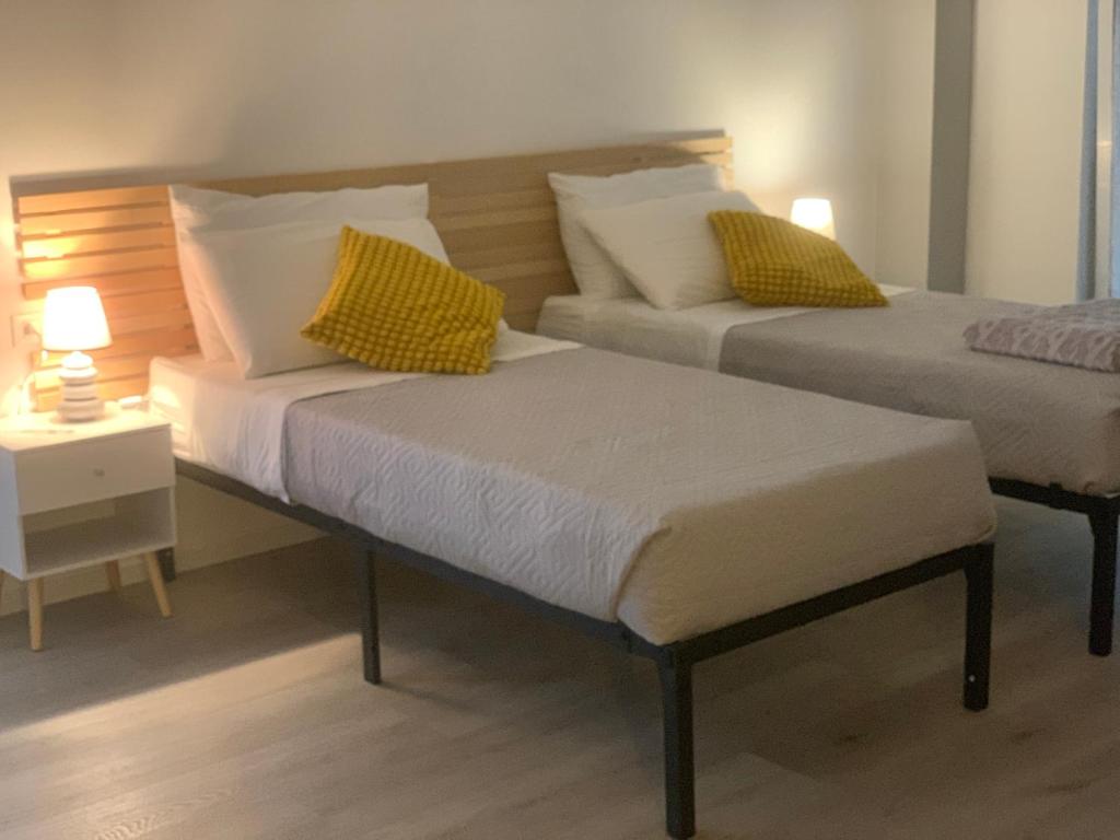 two beds with yellow and white pillows in a room at OnlyRoomsRho in Rho
