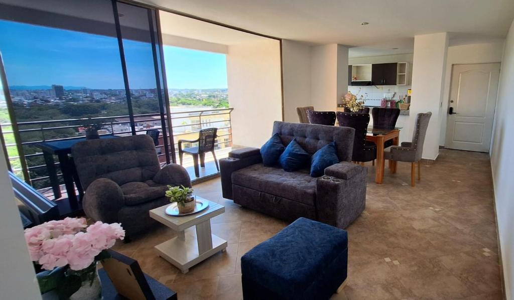 a living room with couches and a table and a kitchen at EM Somos AT HOME Lindo Apartamento con Aire Acondicionado in Neiva