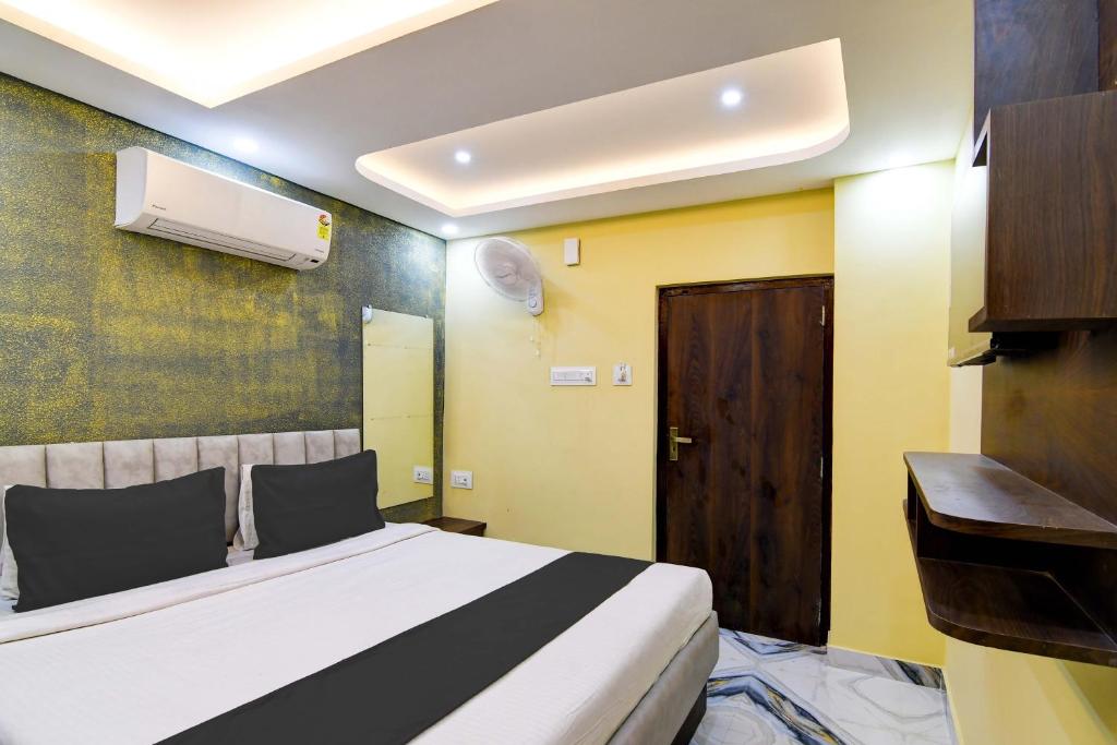um quarto com uma cama branca e uma porta de madeira em The Crown em Calcutá