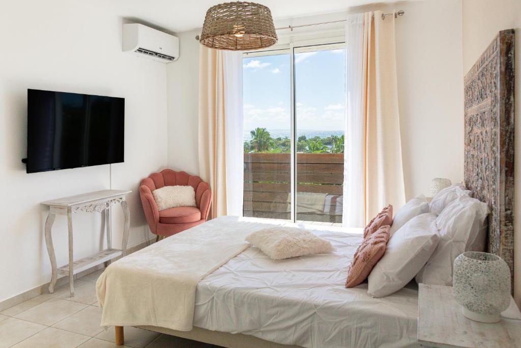 une chambre avec un lit, une télévision et une fenêtre dans l'établissement Villa Ti Papillon, à Saint-François