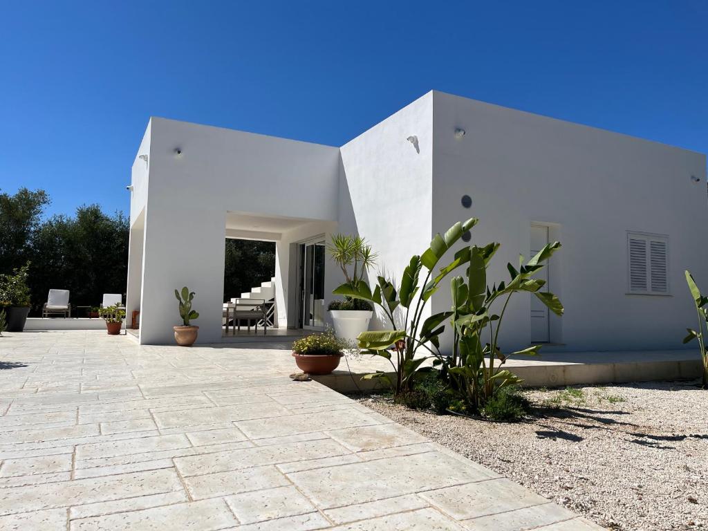 Una casa blanca con plantas delante de ella. en Villa Eraklea, en Marina di Noto