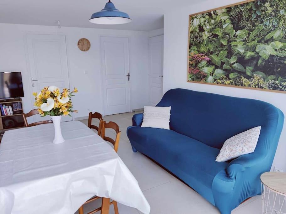 un salon avec un canapé bleu et une table dans l'établissement Gîte des Prés, à La Noë-Blanche