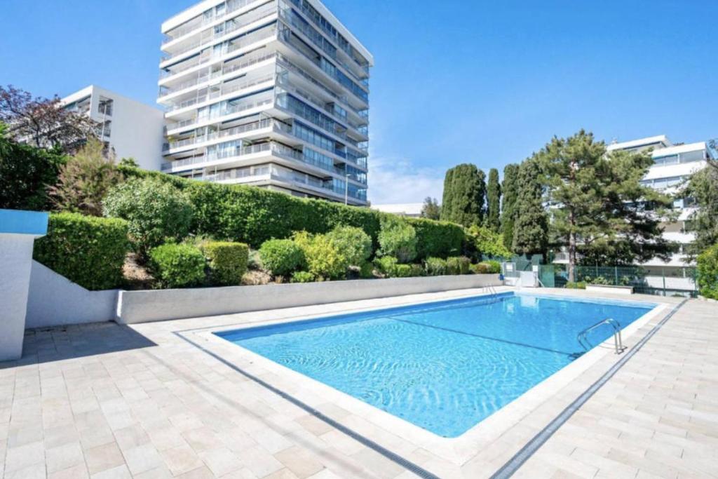 une piscine devant un grand immeuble dans l'établissement Spacieux 2 pièces terrasse et piscine, à Cannes