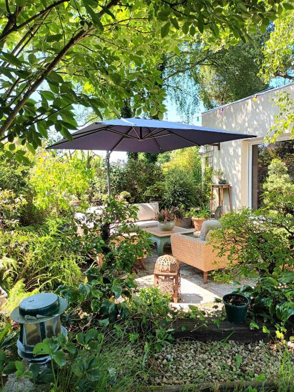 un patio avec une table et un parasol dans l'établissement La maison bric et broc, à Saint-Carreuc