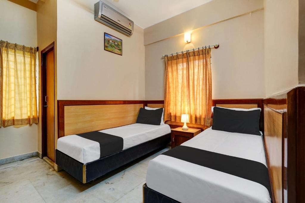 a bedroom with two beds and a window at SPOT ON Benaka Delux Lodging & Delux Rooms in Bangalore