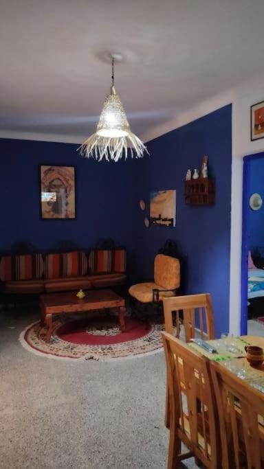 a living room with blue walls and a chandelier at appart J in Essaouira