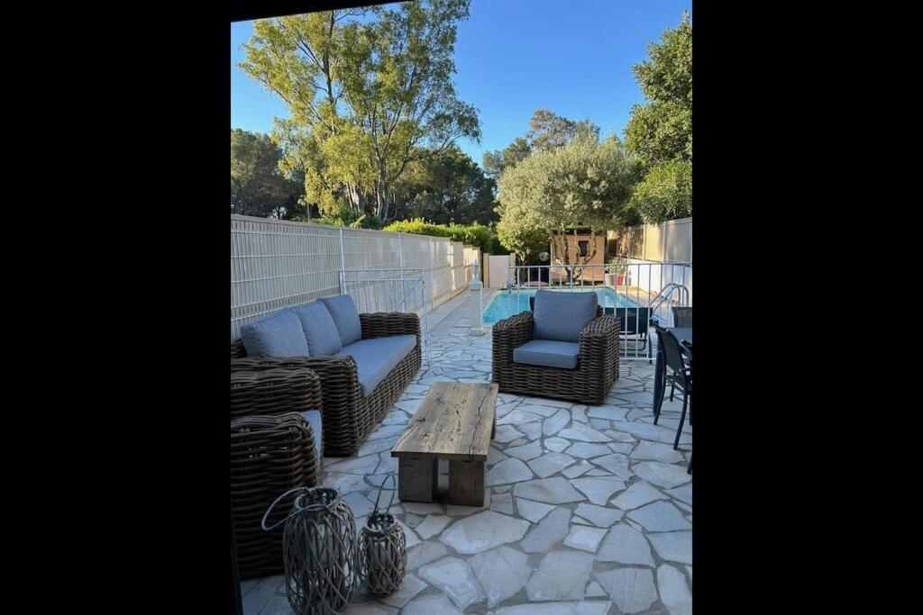 une terrasse avec des canapés, une table et une piscine dans l'établissement Charmant mazet avec piscine privée proche plage et commerces à trois mn à pied à la Croix Valmer, à La Croix-Valmer