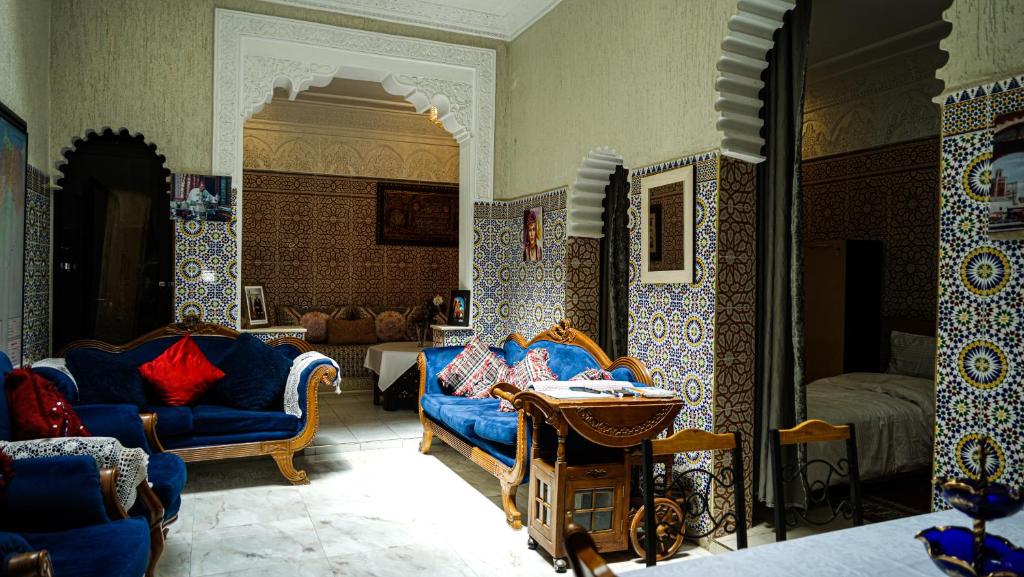 Exquisite Riad Beach & Surf في الرباط: غرفة معيشة مع كراسي زرقاء وسرير