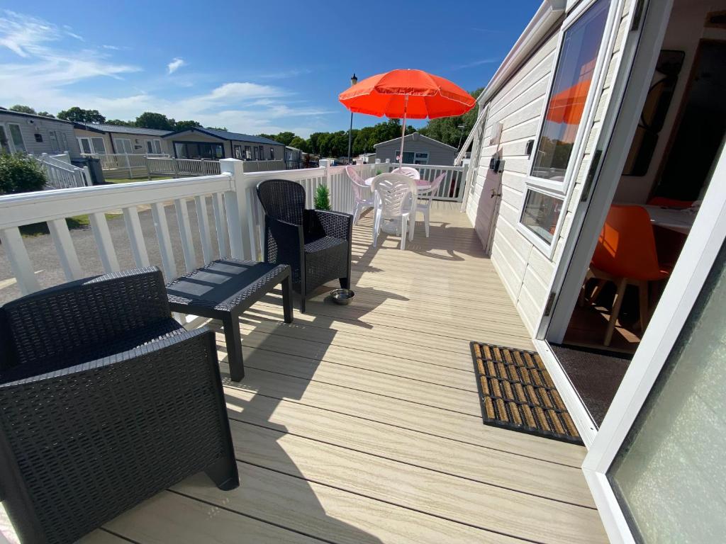 a deck with chairs and an umbrella on a house at Red Squirrel Lodge in Sandown