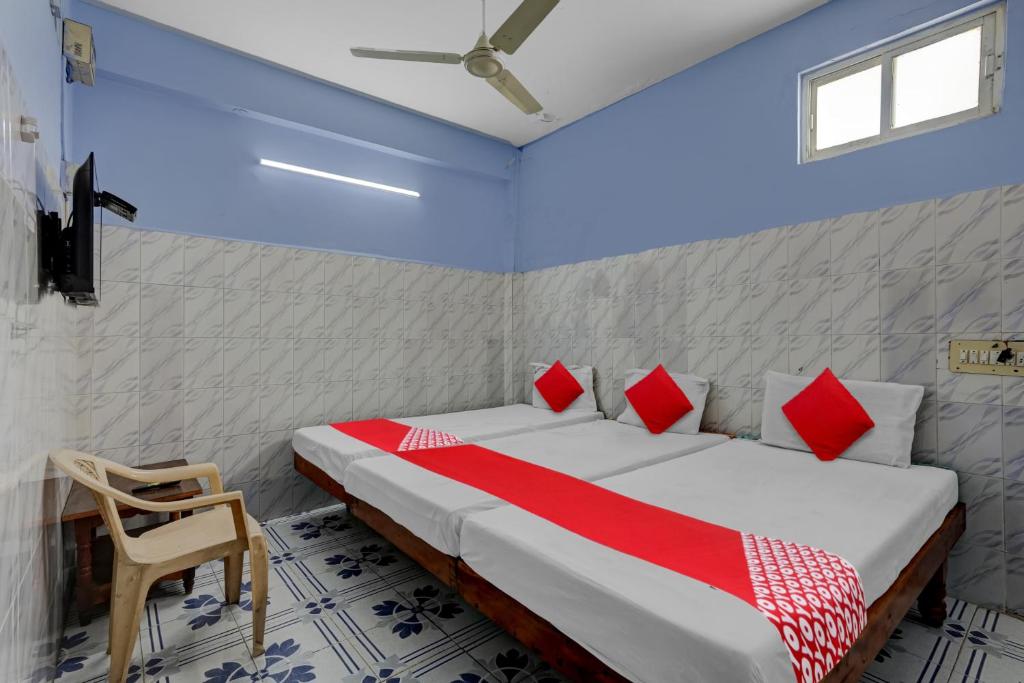 ティルパティにあるOYO Flagship Sai Ganesh Deluxe Lodgeのベッドルーム1室(赤と白の枕が備わるベッド1台付)