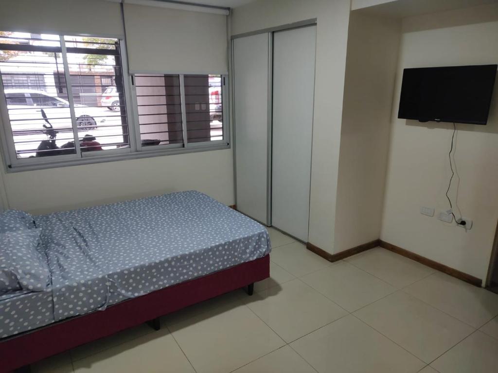 1 dormitorio con cama, ventana y TV en Departamento completo en Rosario