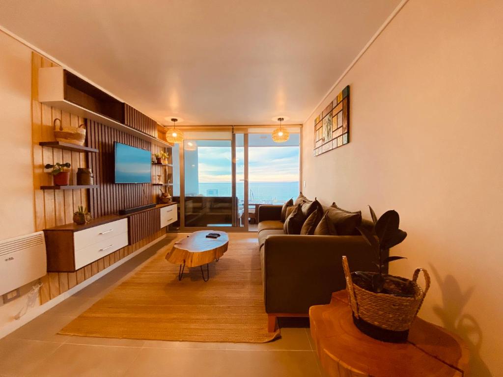 a living room with a couch and a tv at Departamento Concon con Terraza y vista al mar in Concón