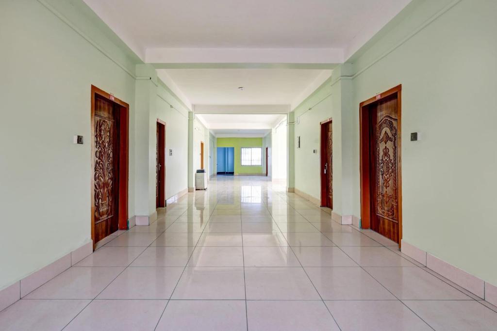 KāhārpāraにあるSPOT ON Sunrise Lodge & Axomiya Dhabaの白壁・白タイルフロアの建物廊下