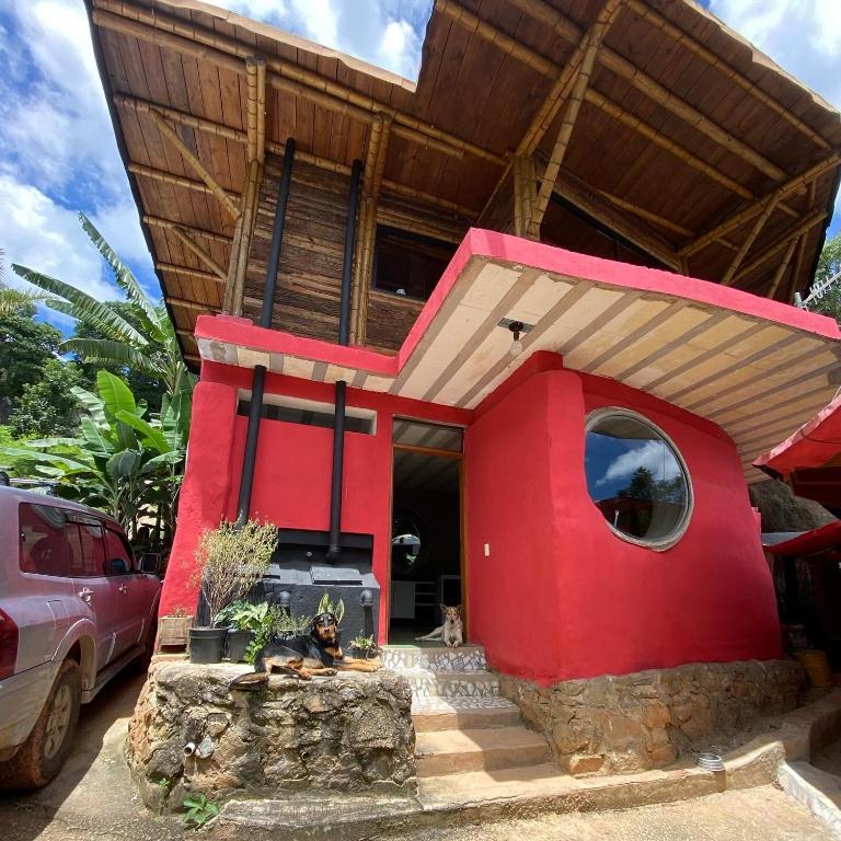 a red house with a dog sitting in front of it at Chalés Sitio Mangala in Itapeva