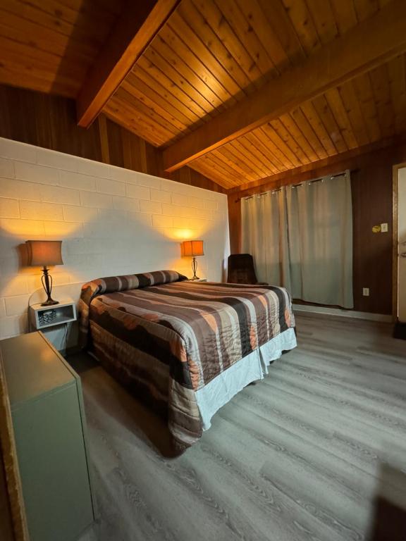 1 dormitorio con cama y techo de madera en Ace Crown Motel, en Medicine Hat