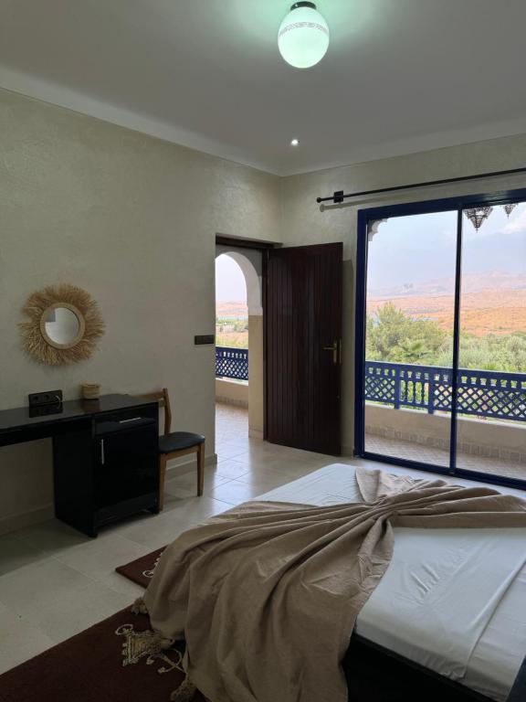 Makhfamane Land في Ouaouizelt: غرفة نوم بسرير ونافذة كبيرة
