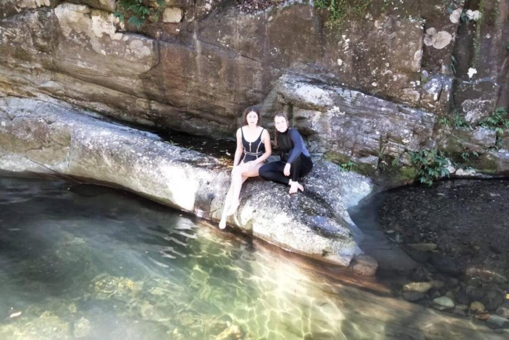a man and woman sitting on a rock in the water at The Cabin Barrington Tops Your Eco Place in Nature in Chichester