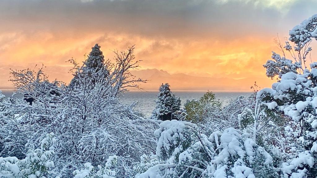 un campo cubierto de nieve con árboles y una puesta de sol en Casita excelente ubicación en San Carlos de Bariloche