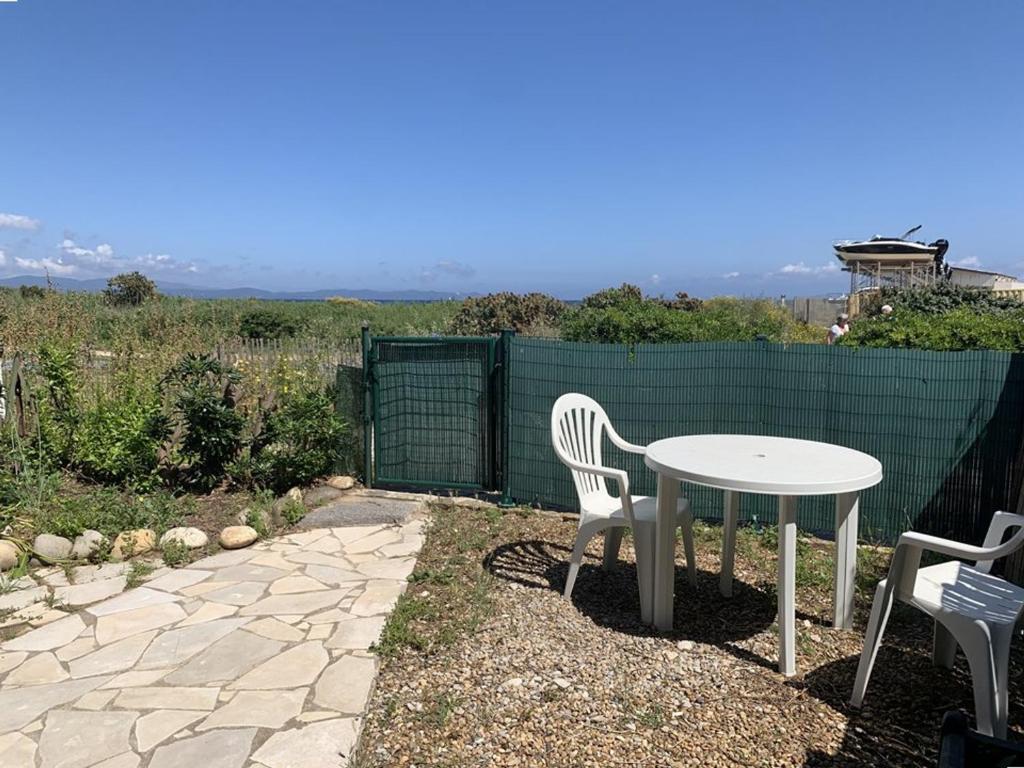 une table et des chaises blanches dans une arrière-cour avec une clôture dans l'établissement T2 Hyères : à 50m de la Plage, Proche du Port, Jardinet Privatif, Idéal Familles - FR-1-335-202, à Hyères