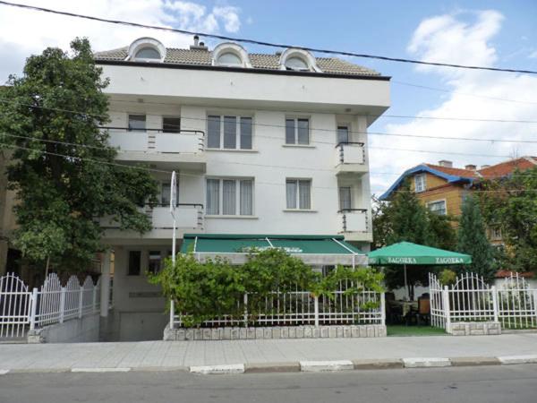 Ein weißes Gebäude mit einem Zaun davor. in der Unterkunft Niko Hotel in Samokow