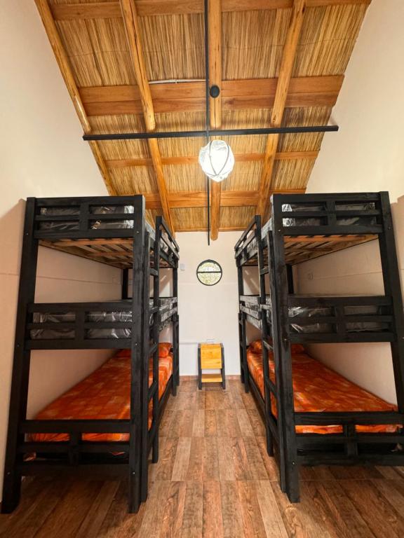 two bunk beds in a room with a wooden ceiling at La Caballeriza Hostel in Tanti Nuevo