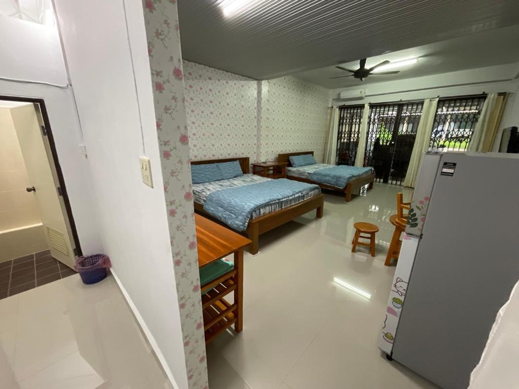 Cette petite chambre comprend deux lits et un réfrigérateur. dans l'établissement MEGIE HOMESTAY PREMIER BETONG Thailand, à Betong