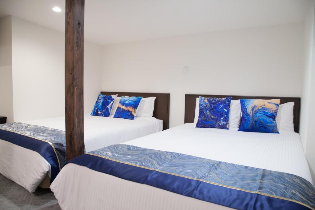 - 2 lits avec des oreillers bleus dans une chambre dans l'établissement NewOpen/Stella Izumisano/泉佐野駅徒歩3分【一棟貸切】関西空港まで 8分, à Izumi-Sano