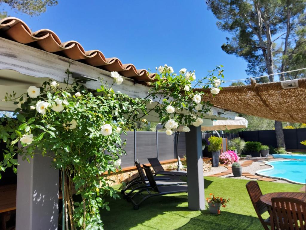 une pergola avec des fleurs blanches et une piscine dans l'établissement Axelore, à Draguignan
