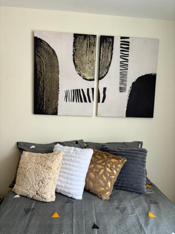 a bed with pillows on it with two pictures on the wall at Departamento Estadio GNP antes foro sol, autodromo hermanos Rodríguez, palacio de los deportes, muy cerca de aeropuerto, CDMX in Mexico City