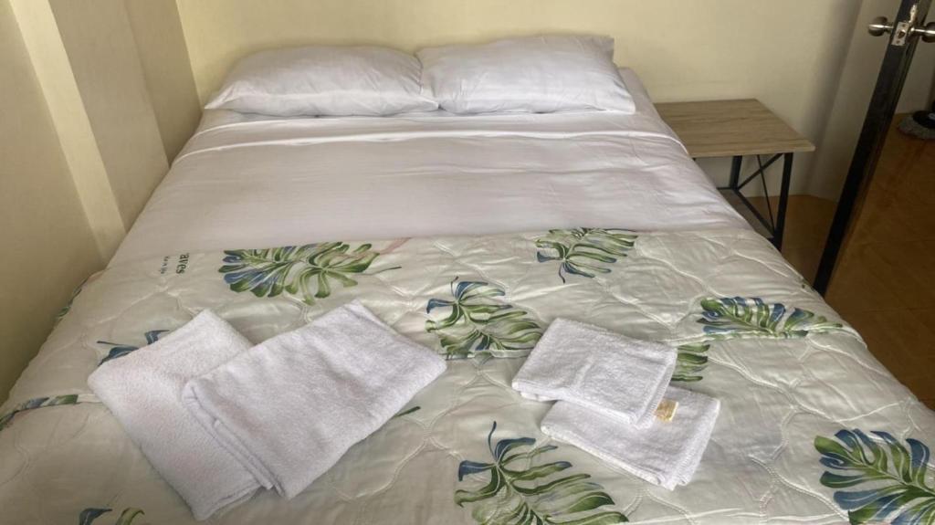 Una cama con sábanas blancas y toallas. en House Audry, en General Trias