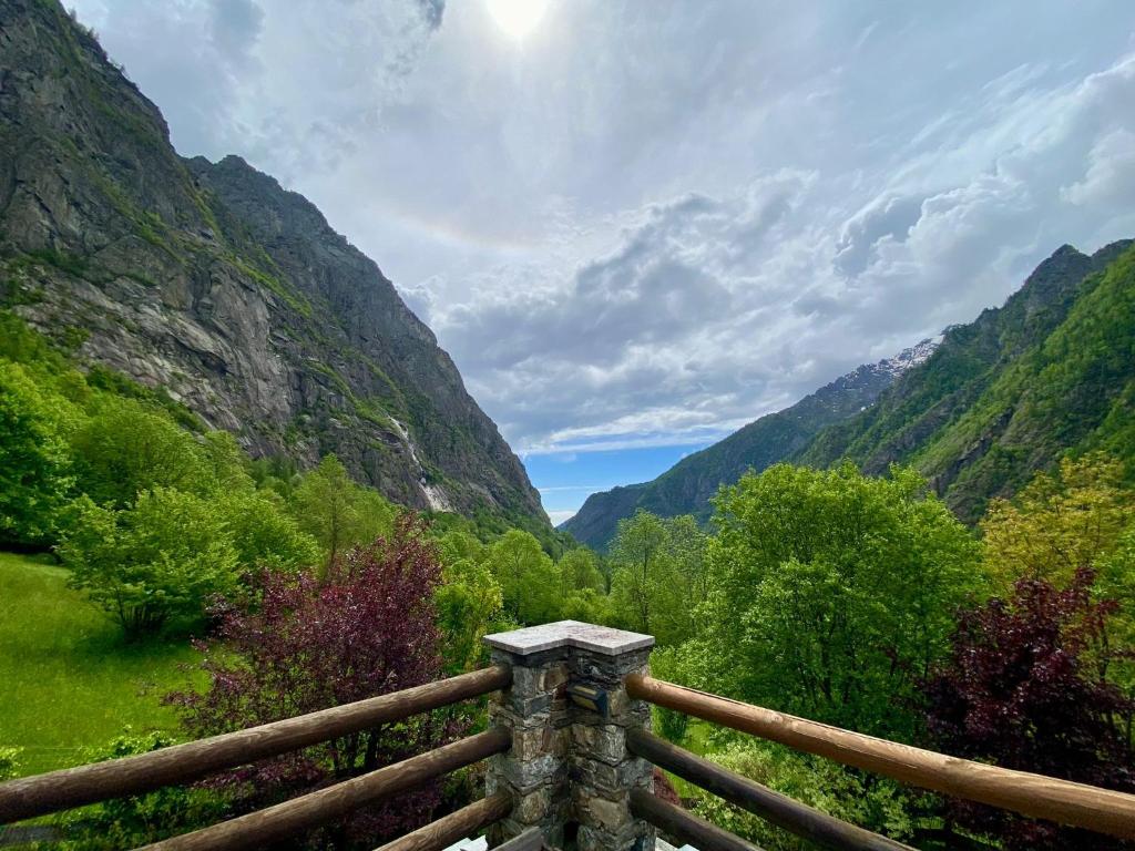 una valla de madera con montañas en el fondo en LA MURA’ - Il vostro posto nel Gran Paradiso en Ronco Canavese