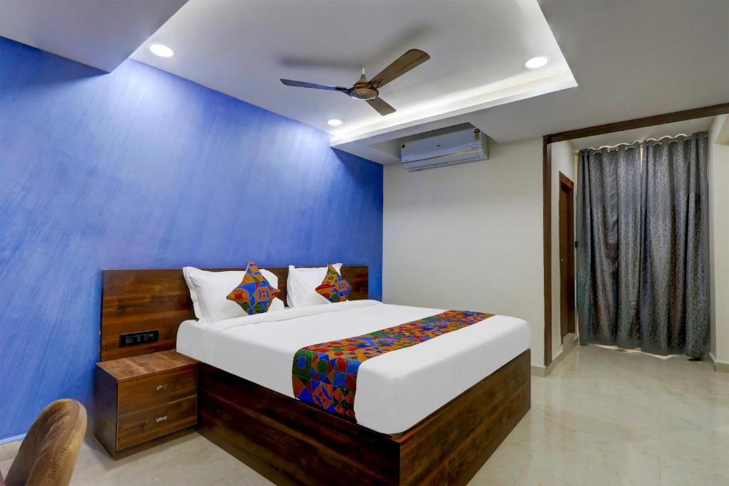 a bedroom with a bed and a blue wall at FabHotel Prime Srishoin in Hyderabad