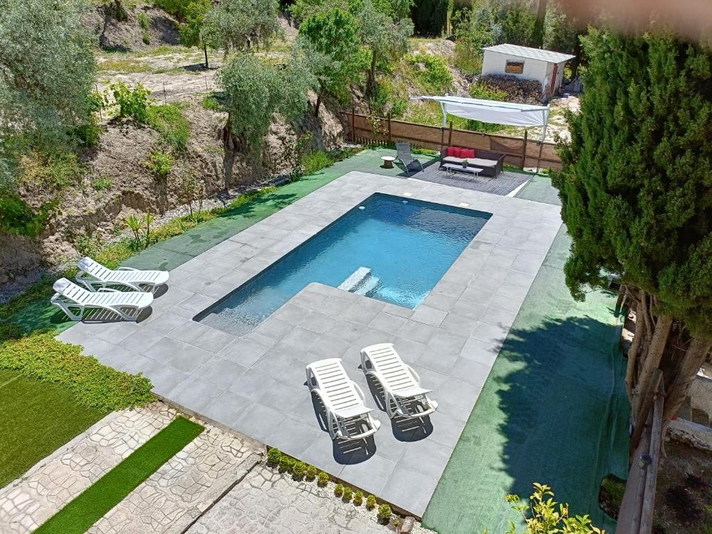 uma vista sobre uma piscina com 2 espreguiçadeiras em Casa Rural La Promesa Granada em Víznar