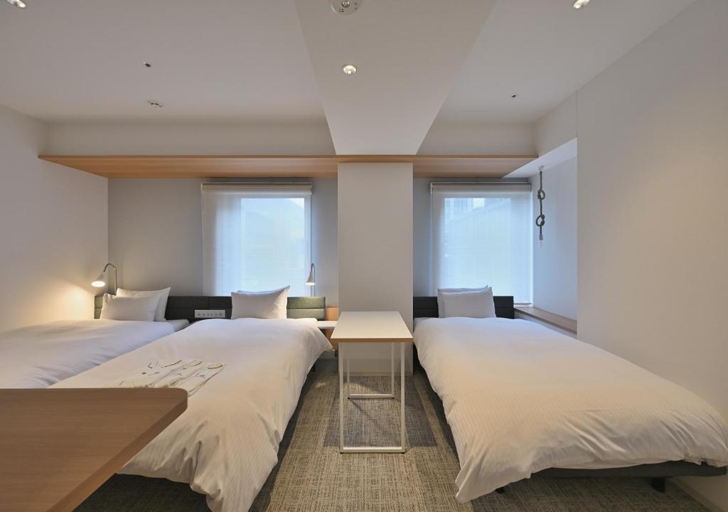 two beds in a room with two windows at Prince Smart Inn Osaka Yodoyabashi in Osaka