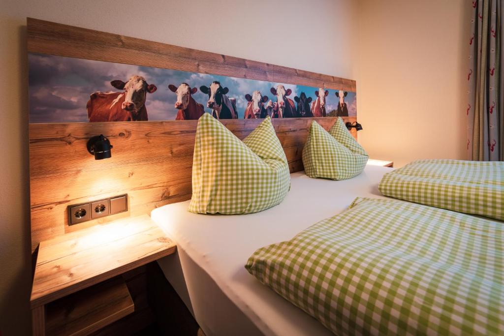 a bedroom with two beds and a picture of cows on the wall at Hotel Garni Landhaus Traunbachhäusl in Ruhpolding