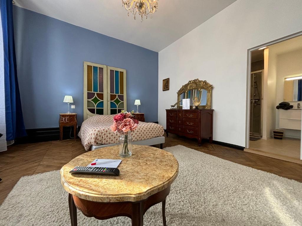 Maison à la Guitarde - Hôtel Particulier Hippolyte في شاتورو: غرفة بها سرير وطاولة عليها زهور