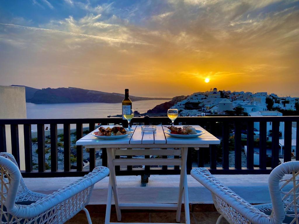 uma mesa com dois pratos de comida e uma garrafa de vinho em Aspa Villas em Oia