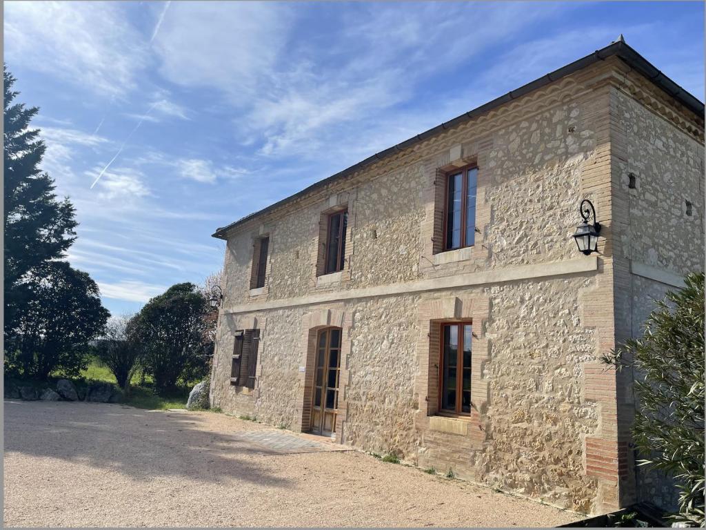 a stone building with windows on the side of it at Gîte Flora in Aubiet