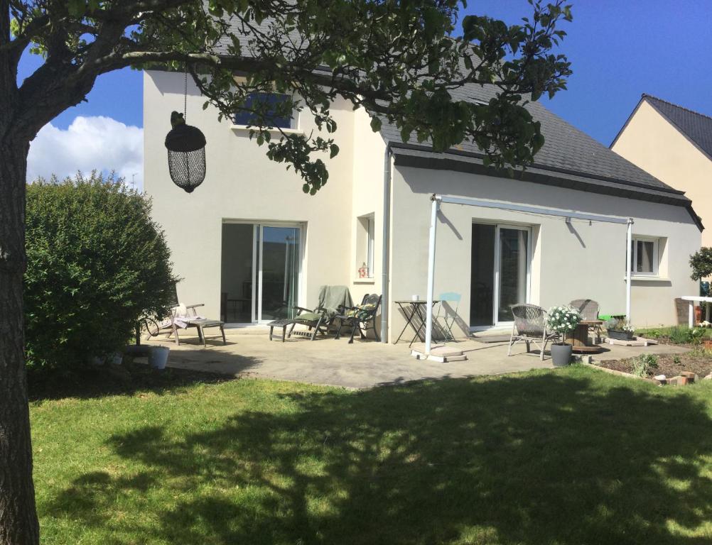 une maison blanche avec des chaises et une terrasse dans l'établissement Maison dans un écrin de verdure, à Saint-Brieuc