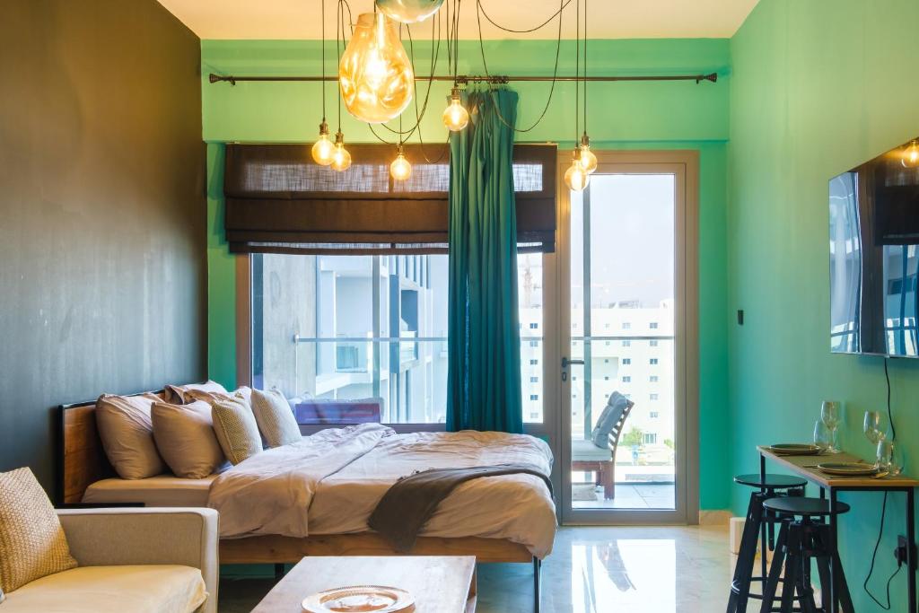 a bedroom with green walls and a bed and a couch at Industrial Chic Retreat in Al Qurayyah