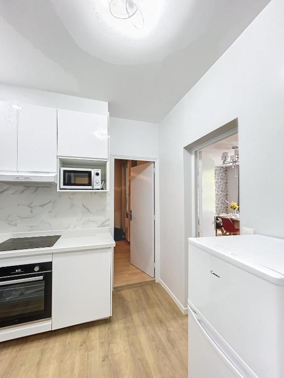 une cuisine avec des armoires blanches et un comptoir dans l'établissement Le Vendangeoir, à Épernay